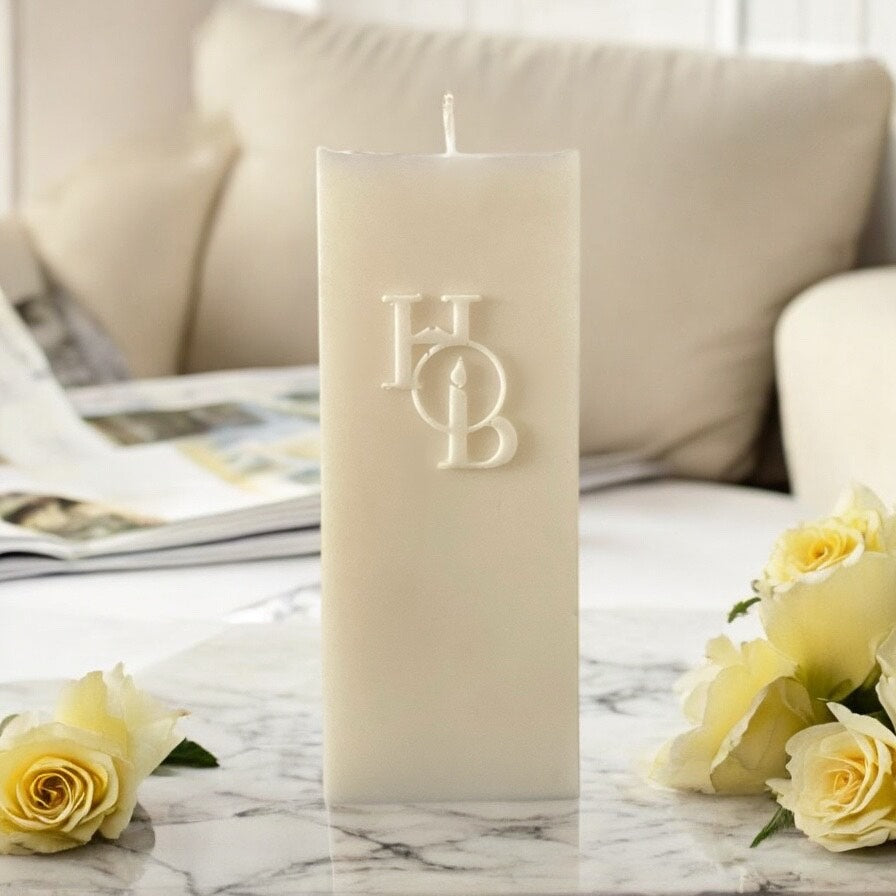 Modern scented pillar candle styled among neutral textures and soft lighting in a curated living space.