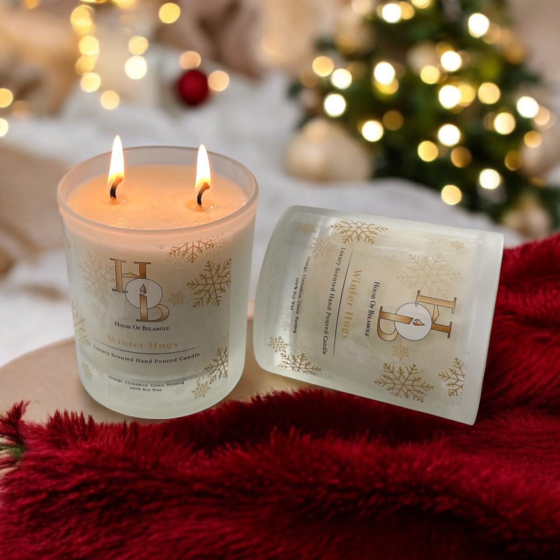 Christmas Scented Candle on a red blanket. Christmas tree and decor in the background